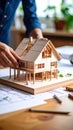 Architect designs wooden house model on blueprints with drafting tools nearby Royalty Free Stock Photo