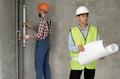 An architect with drawings in his hands. Man supervises construction work with builder. Foreman in house under Royalty Free Stock Photo