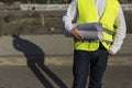 Architect or Engineer man holding blueprints on the Construction Site. Wearing protection clothes. Crane on background over blue Royalty Free Stock Photo