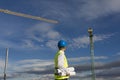 Architect or Engineer man holding blueprints on the Construction Site. Wearing protection clothes. Crane on background over blue Royalty Free Stock Photo