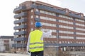 Architect or Engineer man holding blueprints on the Construction Site. Wearing protection clothes. Crane on background over blue Royalty Free Stock Photo