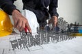 An architect or engineer is working on a desk with architectural and engineering blueprints together with high-rise 3D images Royalty Free Stock Photo
