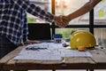 Architect engineers shake hands with hats and houses on construction tool tables. with blueprints on the table - business teamwork Royalty Free Stock Photo