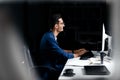 The architect in glasses dressed in a blue jacket sits at the desk and works on the computer in the office Royalty Free Stock Photo