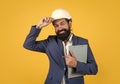 Architect in hardhat holding blueprints and greeting by touching helmet, welcome on board Royalty Free Stock Photo