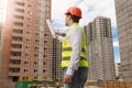 Architect in hardhat pointing with rolled blueprints at building Royalty Free Stock Photo