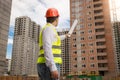 Architect in hardhat and safety vest pointing building with roll Royalty Free Stock Photo