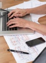 Architect and her tech. Cropped image of an architect working on her laptop with building plans beside her on her desk. Royalty Free Stock Photo