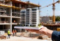 Architect holds building model at construction site with cranes and workers Royalty Free Stock Photo