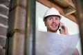 Architect Inside House Being Renovated Studying Plans Talking On Mobile Phone