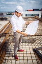 Architect looking at paper plans on construction site. Details of construction building and workers