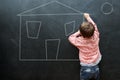 Architect in the making. A little boy drawing a house on a blackboard. Royalty Free Stock Photo