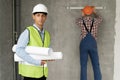 Architect man with blueprints and a working builder in the background against the wall, teamwork at a construction site Royalty Free Stock Photo