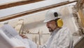 Architect man at work, wearing helmet and headphones looking at blueprint , check the construction house project plan, in Royalty Free Stock Photo