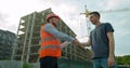 Architect and man engineer shaking hands with blueprint at construction site. Royalty Free Stock Photo