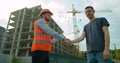 Architect and man engineer shaking hands with blueprint at construction site. Royalty Free Stock Photo