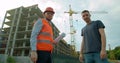 Architect and man engineer shaking hands with blueprint at construction site. Royalty Free Stock Photo