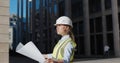 Architect in protective helmet holding blueprint in front of office building Royalty Free Stock Photo