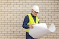 Architect in a protective helmet holds a layout plan