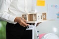 Sustainable Building Model Presentation. Professional holding eco-friendly design model in meeting. Royalty Free Stock Photo
