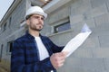 Architect stood outside house looking at plans Royalty Free Stock Photo