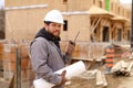 Architect talking by walkie talkie and holding drawing plan at construction site. Royalty Free Stock Photo