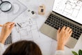 Architect typing laptop keyboard to review design of house before editing with compass