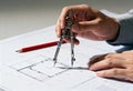 Architect using a drawing compass on a blueprint. Engineer working on a technical floor plan for a construction project Royalty Free Stock Photo