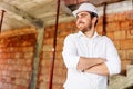 architect visiting the construction site. Portrait of construction worker with brick walls