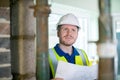 Architect Wearing Hard Hat Inside House Being Renovated Studying Plans