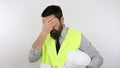 Architect wearing reflective jacket holding safety helmet under arm, tired with hand on forehead feeling fatigue and headache. Royalty Free Stock Photo