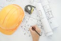 Architect working on construction blueprint. Architects workplace - architectural project, blueprints, helmet, measuring tape