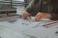 An architect is working in the office, there are blueprint and house model on the desk, engineer is checking overall of work that Royalty Free Stock Photo