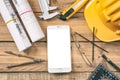 Architect workplace. Smartphone with white, blank screen, project construction blueprints and engineering tools on wooden desk, co Royalty Free Stock Photo