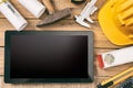 Architect workplace. Tablet with black blank screen, project construction blueprints and engineering tools on wooden desk, copy sp Royalty Free Stock Photo