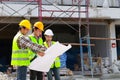 Architects, engineers and contractors holding construction drawings outdoor meeting in construction site. Royalty Free Stock Photo