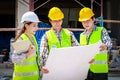 Architects, engineers and contractors holding construction drawings outdoor meeting