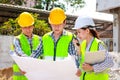 Architects, engineers and contractors holding construction drawings outdoor meeting in construction site. Royalty Free Stock Photo