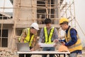 Architects and engineers working together sketching building plans and discussing at construction site wearing uniforms Royalty Free Stock Photo