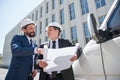 Architects in hardhats discussing blueprint while standing outdoors