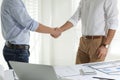 Architects shaking hands near table with construction projects in office, closeup Royalty Free Stock Photo