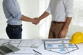 Architects shaking hands near table with construction projects in office, closeup Royalty Free Stock Photo