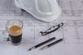 Architects workplace - architectural blueprints with safety helmet, glasses, coffee and propelling pencil on table. Top view. Royalty Free Stock Photo