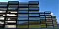 Architectural abstraction. Panoramic windows of numerous high-rise buildings. Reflection of the blue sky and green meadows in the Royalty Free Stock Photo