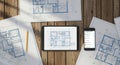 Architectural blueprints and digital devices on a wooden surface Royalty Free Stock Photo