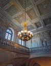 Architectural details of a ornate staircase hall with a glowing vintage chandelier hanging from ceiling at Versailles Palace, Royalty Free Stock Photo