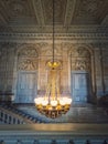 Architectural details of a staircase, ornate hall and glowing vintage chandelier hangs from ceiling, Versailles Palace, France