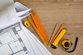 Architectural drawings and pencils, ruler, tape-measure, clerical knife on wooden background. Top view. Repair housing concept