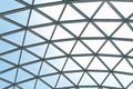 Architectural glass structure with a geometric triangular pattern on a blue sky background. Steel glass roof wall Royalty Free Stock Photo