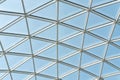 Architectural glass structure with a geometric triangular pattern on a blue sky background. Steel glass roof wall Royalty Free Stock Photo